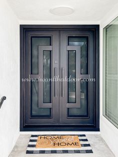 the front door to a home with a welcome mat and black double doors on both sides