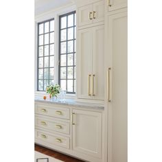 a kitchen with white cabinets and marble counter tops in front of a large window that looks out onto the outdoors