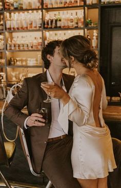 a man and woman kissing while sitting at a bar