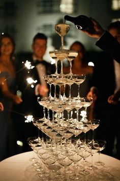 a large stack of wine glasses sitting on top of a white table covered in sparklers