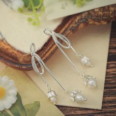 Elevate your elegance with our Silver Lily Of The Valley Bow Earrings. Crafted in sterling silver, these delicate earrings showcase the iconic Lily of the Valley motif in a charming bow design. A touch of femininity and nature-inspired grace, these earrings are perfect for adding a subtle yet timeless accent to your look.  🎀 DETAILS Materials:  Sterling  Silver, Pearl Size: 2.09"* 0.31 "(5.3cm*0.8cm) Weight: 7.4g/pr Sterling Silver Drop Clip-on Earrings For Gift, Delicate Silver Drop Flower Earrings, Silver Drop Flower Earrings Gift, Silver Sterling Pearl Drop Flower Earrings, Silver Sterling Flower Earrings With Pearl Drop, Classic Pearl Drop Flower Earrings Gift, Delicate Silver Dangle Flower Earrings, Silver Flower Earrings With Pearl Drop, Delicate Silver Earrings With Ear Wire