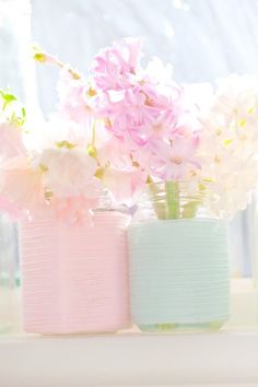 three pastel colored vases with flowers in them