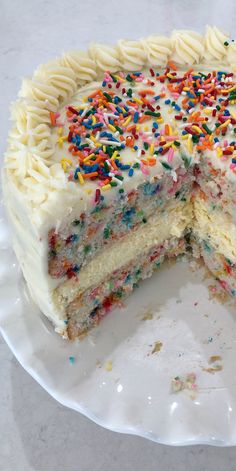 a cake with white frosting and colorful sprinkles on the top is cut in half