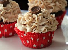 three cupcakes on a plate with white polka dot paper and chocolate frosting