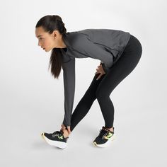 a woman in black and grey is stretching her legs with one hand on her hip