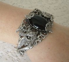 This beautiful silver plated filigree cuff bracelet has silver plated dragons, silver plated accents and a black onyx setting. Adjustable. Elegant Adjustable Dragon Design Jewelry, Elegant Adjustable Jewelry With Dragon Design, Gothic Metal Jewelry With Dragon Design, Silver Dragon Design Jewelry For Formal Occasions, Ornate Silver Hand Cast Jewelry, Silver Jewelry With Dragon Design For Formal Occasions, Formal Silver Jewelry With Dragon Design, Adjustable Silver Fantasy Bracelet, Silver Gothic Collectible Jewelry