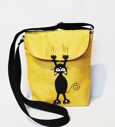 a small yellow purse with a black cat on it's front and shoulder strap