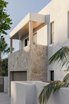 a modern house with stone walls and palm trees