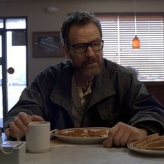 a man sitting at a table with a plate of food