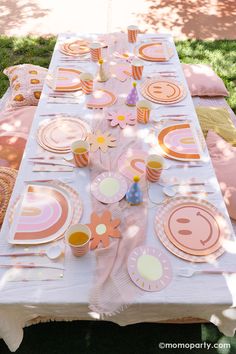 a table set up with plates, cups and utensils for a birthday party