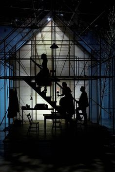 silhouettes of people sitting at a table in front of a house under construction with scaffolding