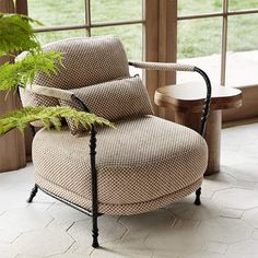 a chair sitting in front of a window next to a plant