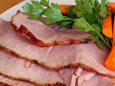 slices of ham on a plate with carrots and parsley