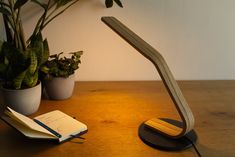 a desk with a lamp, notebook and potted plants