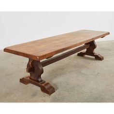 an old wooden bench sitting in the middle of a concrete floored area with white walls behind it