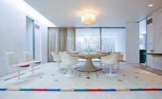 a dining room with white chairs and a round table surrounded by colorful tiles on the floor