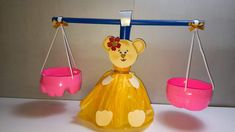 a toy bear sitting on top of a scale with two pink bowls hanging from it's sides