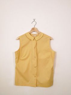 Vintage 1960s Mellow Yellow Sleeveless Blouse/Women's Shirt. Measurements Length: 23" Armpit to armpit : 19 1/2" Shoulder: 14 1/2" Condition: Gently used. There's no stains or holes. Good condition.  ※Please read the policy before you purchase※ Affordable Vintage Yellow Shirt, Cheap Yellow Vintage Blouse, Vintage Yellow Sleeveless Top, Yellow Sleeveless Vest For Work, Retro Summer Tops With Peter Pan Collar, Yellow Retro Sleeveless Tank Top, Retro Yellow Sleeveless Tank Top, Classic Sleeveless Top For Daywear, Vintage Workwear Tops With Peter Pan Collar