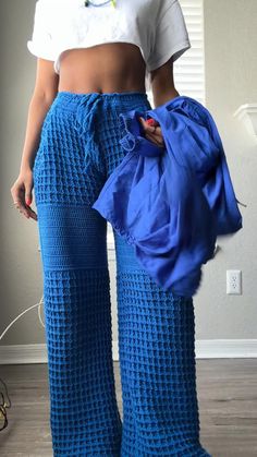 a woman wearing blue pants and holding a bag in her right hand while standing on the floor