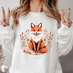 a woman wearing a white sweatshirt with an orange fox on it's chest and two fingers in the air