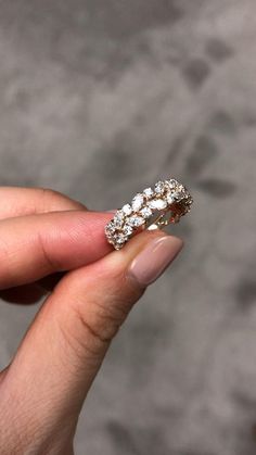 a woman's hand holding a ring with three small diamonds on top of it