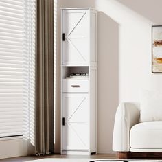 a living room with a white couch and tall cabinet in the corner next to a window