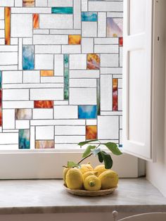 a bowl of fruit sitting on top of a window sill next to a glass block wall