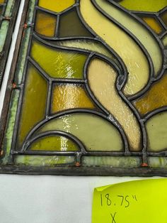 an old stained glass window with yellow and green designs on the outside, next to a ruler