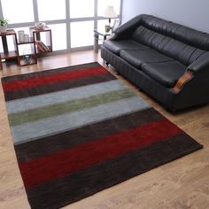 a black leather couch sitting next to a rug on top of a hard wood floor