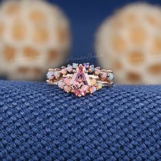 a pink diamond ring sitting on top of a blue blanket