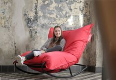 a woman sitting on a red chair in front of a wall