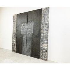 two black and white paintings on a wall in an art gallery, one is made out of bricks