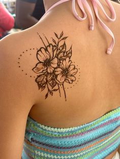 the back of a woman's shoulder with flowers painted on her arm and chest