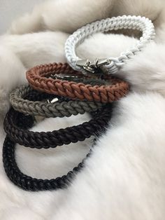 four different colored braided bracelets sitting on top of a white fur covered surface