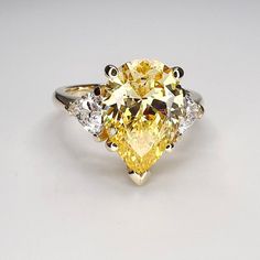 "This ring is a pear shape canary yellow simulated diamond with trillion accents made with solid 14k white gold item #5402 -Approximate total carat weight:  4.80ctw diamond equivalent  -Center Stone Size: 13x9mm  approx. 4.00ct diamond equivalent -Gem Type:  simulated diamond -Stone Shape:  pear shape  -Stone Clarity: VVS1 -Stone Color: canary yellow -Moh's Scale:  8.5 Hardness -Accent Stones: 2 trillions  -Stone size: 5x5mm approx 0.40ct each diamond equivalent -Gem Type:  simulated diamond -Me Yellow Pear Diamond Engagement Ring, Elegant Yellow Pear-shaped Diamond Ring, Yellow Diamond Pear-shaped Ring, Yellow Pear-shaped Diamond Rings, Pear-shaped Yellow Diamond Ring For Wedding, Pear-shaped White Gold Rings With Diamond Cut, Classic Yellow Diamond Ring With Accents, Pear-shaped Brilliant Cut Cubic Zirconia Ring, Fine Jewelry Yellow Pear-shaped Ring