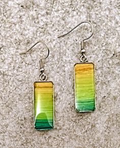 These ombre style dangle earrings are created using very intense inks and are really pretty to wear. They are set in surgical steel which is hypoallergenic and non tarnish too. They are coated with a thick double  layer of resin which protects the colors, also makes them very luminous and durable.Each pair comes with a description card and a gold satin gift bag Green Dangle Earrings Cadmium-free, Artistic Green Earrings For Gift, Green Hand Painted Drop Earrings, Green Cadmium-free Dangle Earrings, Unique Green Long Drop Earrings, Artsy Green Earrings With Ear Wire, Artistic Green Jewelry With Matching Earrings, Green Long Drop Earrings As Gift, Green Long Drop Earrings For Gift