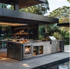 an outdoor kitchen is built into the side of a house with large windows and sliding glass doors