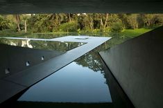 the reflection of trees in the water is seen from under an overhanging walkway