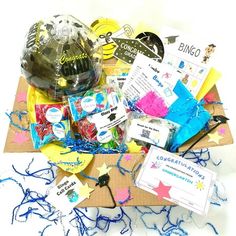 a box filled with lots of different items on top of a white table covered in confetti