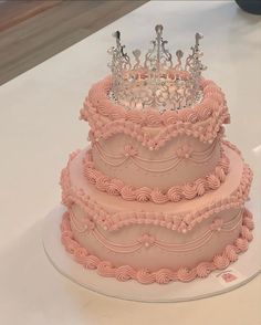 a three tiered pink cake with a crown on top