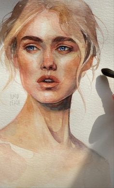 a woman's face is drawn on a piece of paper with watercolor pencils