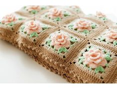 a close up of a crocheted cloth with pink flowers on it's edges