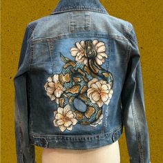 a denim jacket with a snake and flowers on it