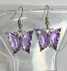 Adorable purple butterfly earrings are just the thing to adorn your earlobes with flash and color, without being too much. Perfect for when long dangly earrings just won't do.These measure 1.5" (Approximate measurement, includes ear wire) Stainless Steel ear wires, metal alloy and glass charm. Any metals used in jewelry are Zinc alloy (lead and nickel free), tarnish resistant (except for copper, which will change color(patina) over time). Metals are either bare copper, silver-tone, or gold-tone, Playful Cheap Purple Earrings, Affordable Purple Trendy Earrings, Cheap Purple Jewelry For Festival, Purple Butterfly Charm Jewelry For Party, Purple Metal Earrings As Gift, Purple Metal Earrings For Gift, Single Purple Drop Earring, Trendy Lavender Earrings For Gift, Butterfly Party Earrings With Ear Wire