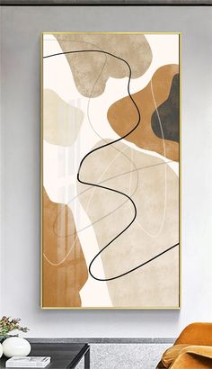 an abstract painting hangs on the wall next to a brown chair and table in a living room