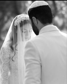 the bride and groom are looking at each other in black and white, with trees in the background