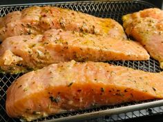 three pieces of cooked salmon sitting on top of a metal grill grate with seasoning sprinkles