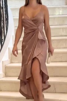 a woman in a dress is walking down the stairs with her hand on her hip