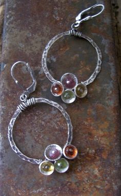 These super sweet colorful sterling silver gemstone hoop earrings from the Tiny Bubbles Collection feature multi-colored gemstones. They are hand textured sterling silver hoops are dotted with sterling silver cups and filled with peridot, carnelian , citrine and pink tourmaline. The hoops are 1' in diameter and are hung from oxidized sterling silver leverbacks. They come in a gift box perrfect for gift giving or safe keeping. Multicolor Nickel-free Jewelry For Anniversary, Fusion Style Sterling Silver Hoop Earrings As Gift, Unique Multicolor Small Hoop Jewelry, Unique Gemstone Hoop Jewelry, Sterling Silver Circle Birthstone Jewelry, Silver Dangle Hoop Earrings With Natural Stones, Unique Round Hoop Earrings With Natural Stones, Multi-stone Hoop Jewelry For Gifts, Silver Circle Gemstone Jewelry