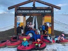 group of people sitting on rafts in front of a sign for the colorado adventure park